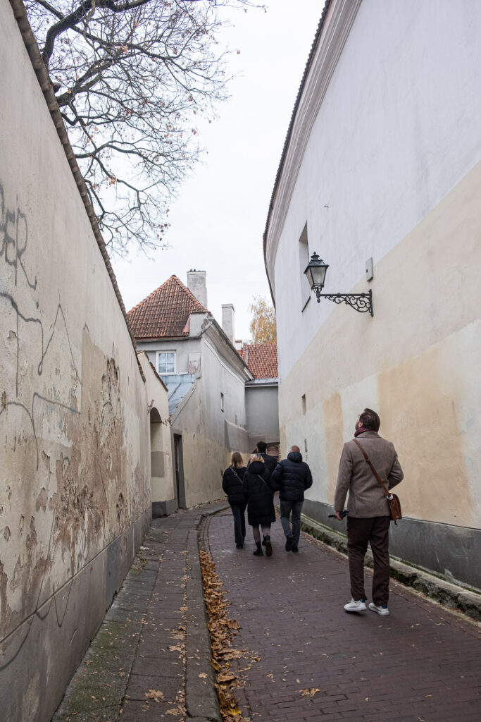 a group of people walking in a narrow street in the old town of vilnius