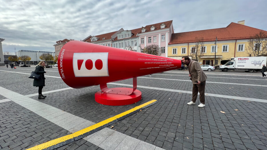 en mann og en dame leker med en stor megafon på torget i gamlebyen i vilnius