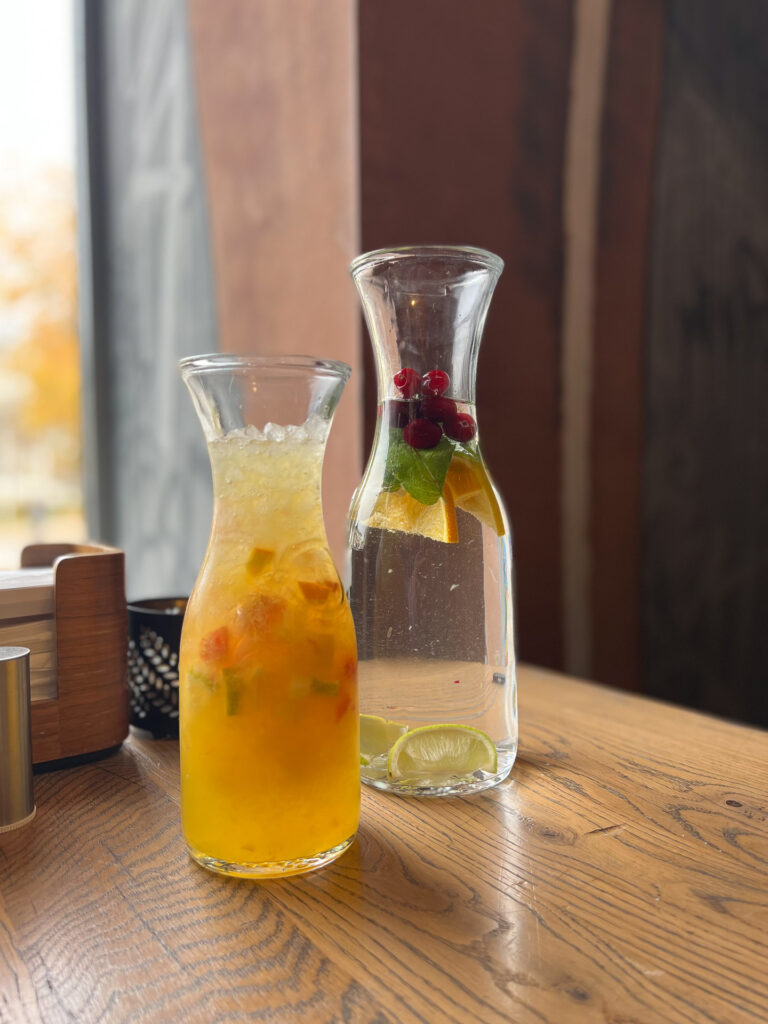 a jug of juice and a jug of water filled with fresh fruit on a table