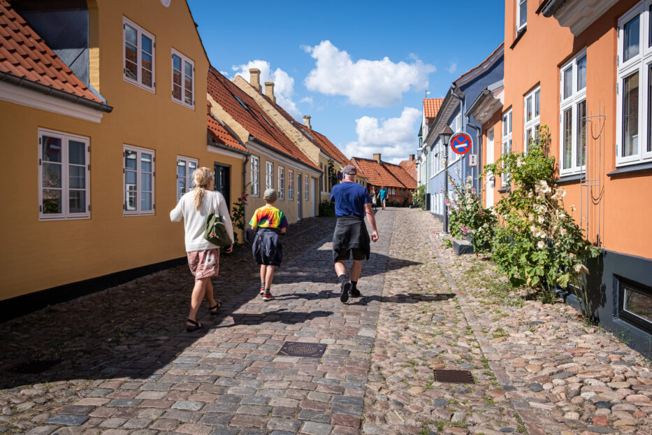 woman boy and man walking down the cobblestone street of ebeltoft