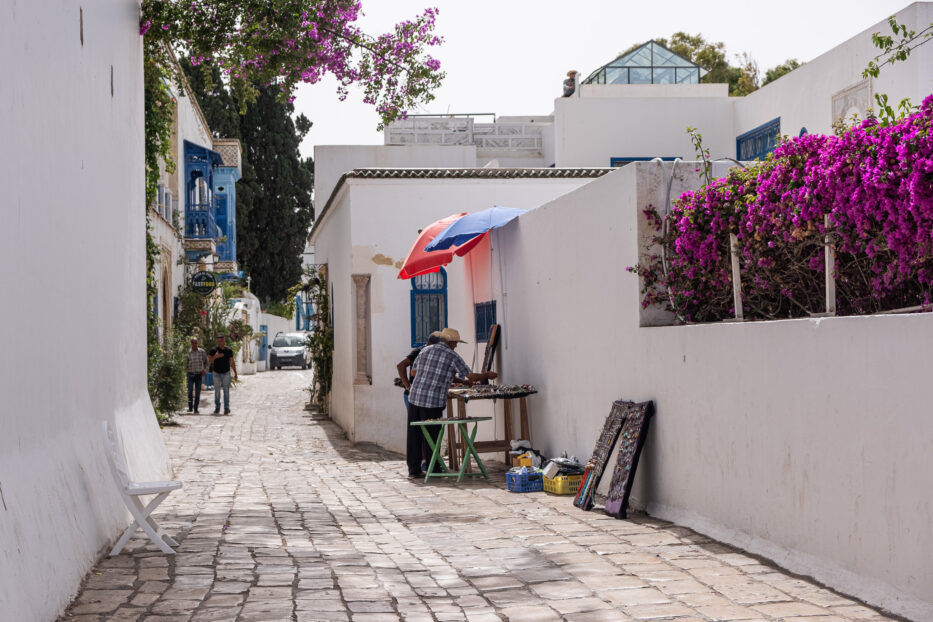 to menn står foran et bord og snakker i en av sidi bou saids mange brosteinsbelagte gater