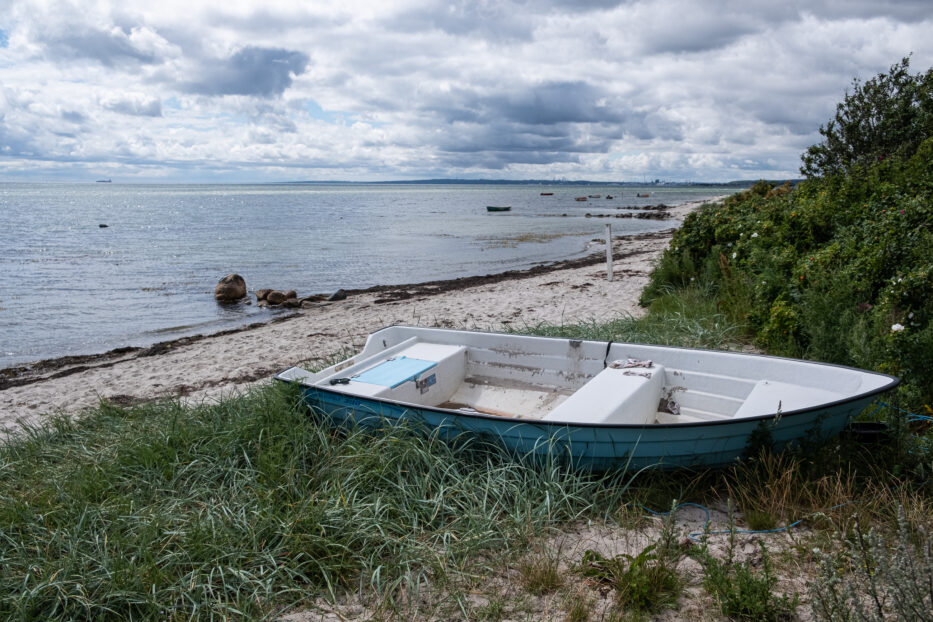 a small row boat laying on the beach in jutland