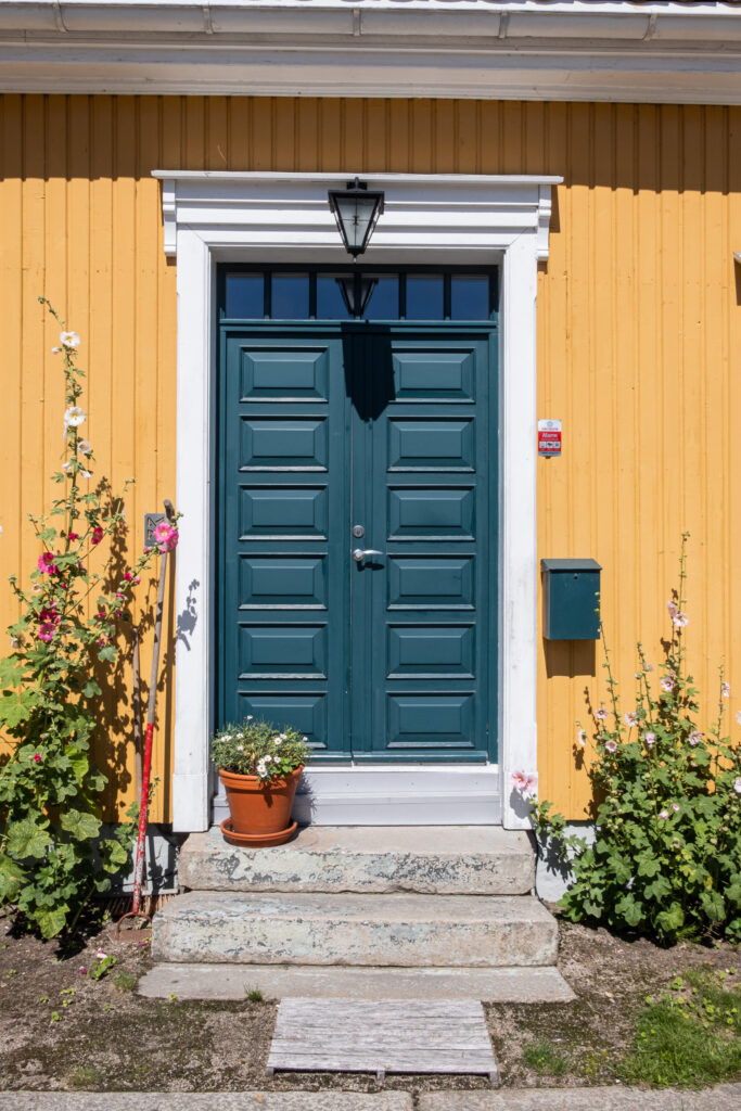 a yellow house with a green door decorated with flowers