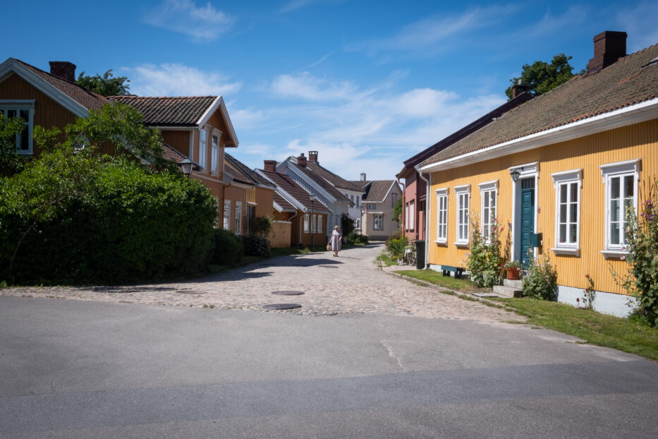 en kvinne går gjennom brosteinsgatene i vaterland mellom fargerrike trehus