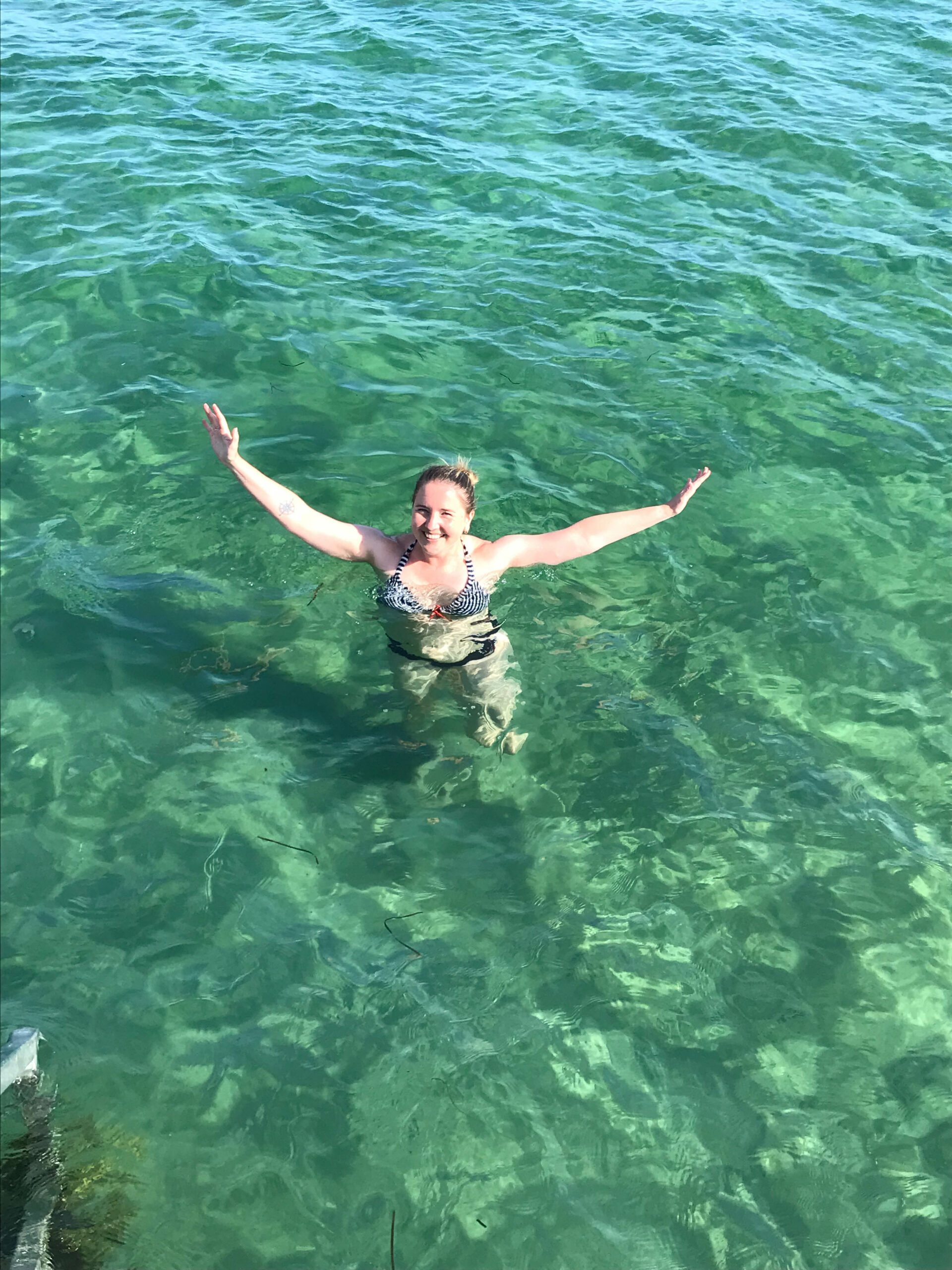 smiling woman waving while having a swim in the sea