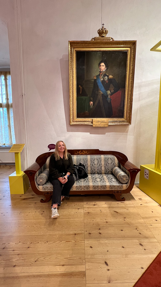 woman sitting on fancy couch in front of large painting inside örebro castle