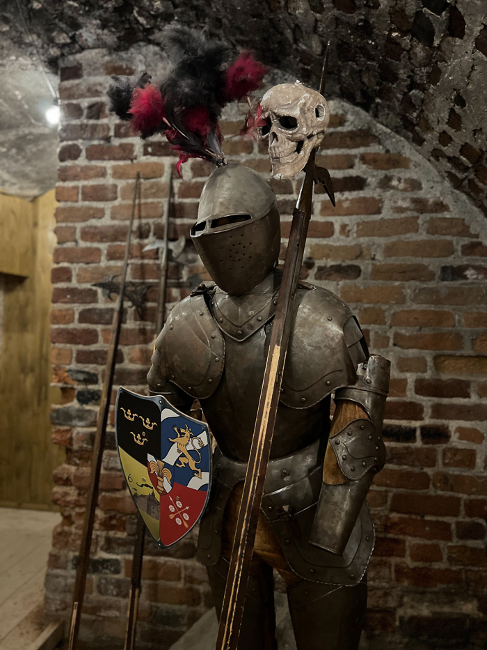en rustning med skjold og en hodeskalle på en bajonett står utstilt inne på örebro slott