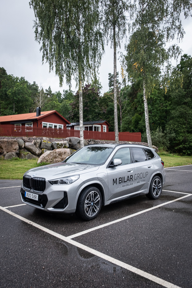 a grey car with the text m bilar group on the side parked outside Katrinelund Gästgiveri & Sjökrog