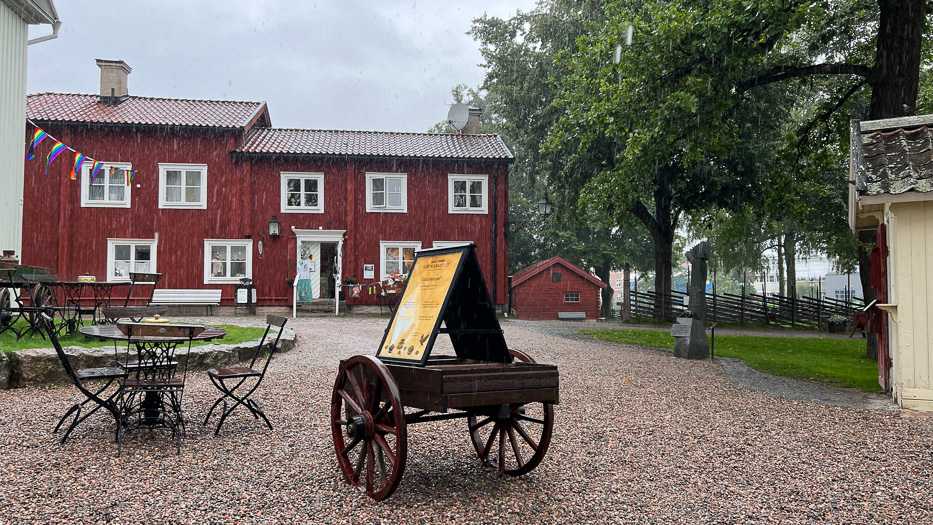 mye regn i wadköping med en gammel vogn og et gult skilt foran røde trehus