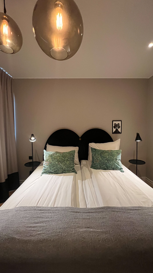 inside a bedroom at Clarion Collection Borgen bedside with green pillows and an image of a dog with a bow in the background