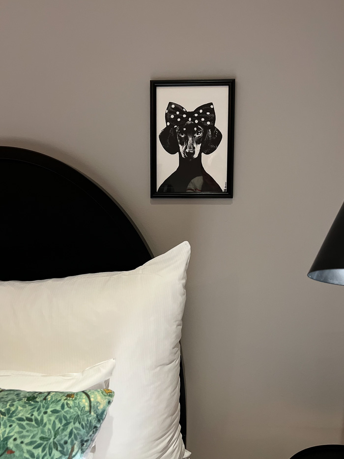 detail from bedroom at Clarion Collection Borgen bed with a green and a white pillow and an image of a dog with a bow on the wall