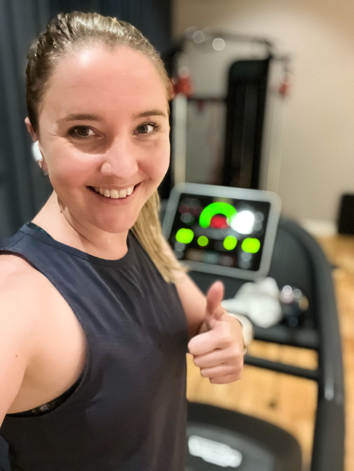 woman with ponytail wearing active wear while standing on a threadmill at Clarion Collection Borgen giving thumbs up to the camera