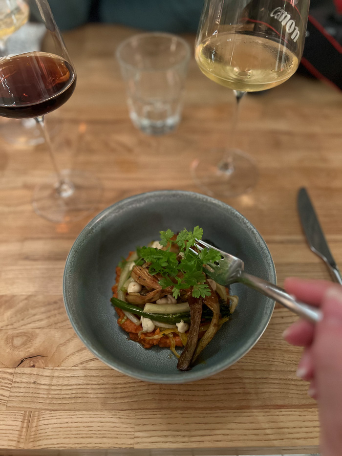 person holding a fork with a dish with veggis