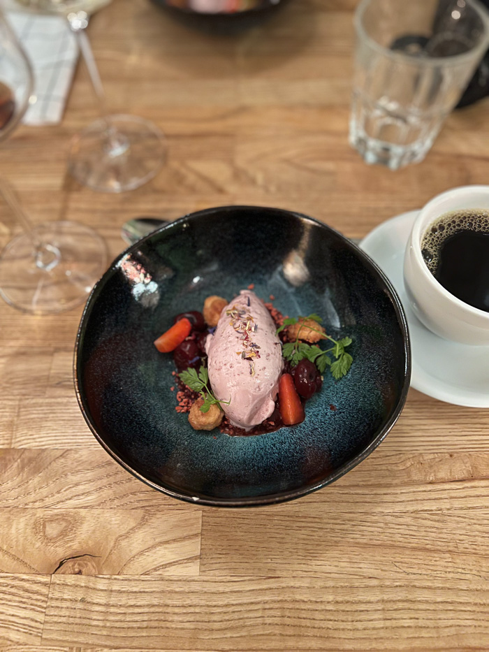 a round bowl with ice cream and some garnish and a cup of coffee next to it