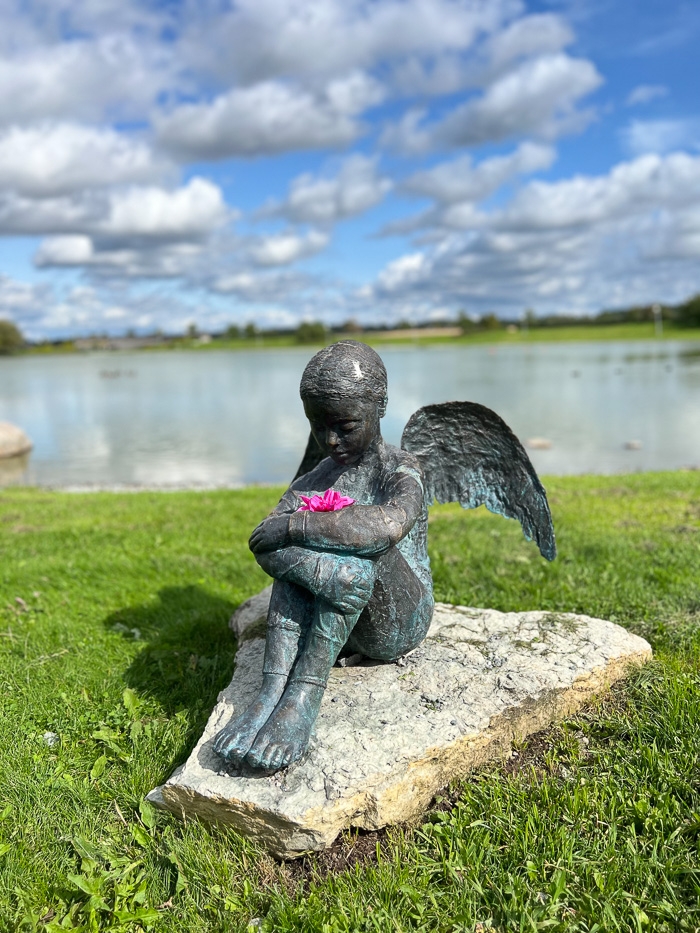 a statue of an angel outside goda rum with the fake lake in the background