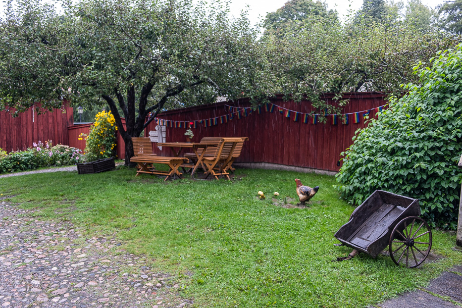 a green backyard with some furnitures on a grey day with red houses in the background