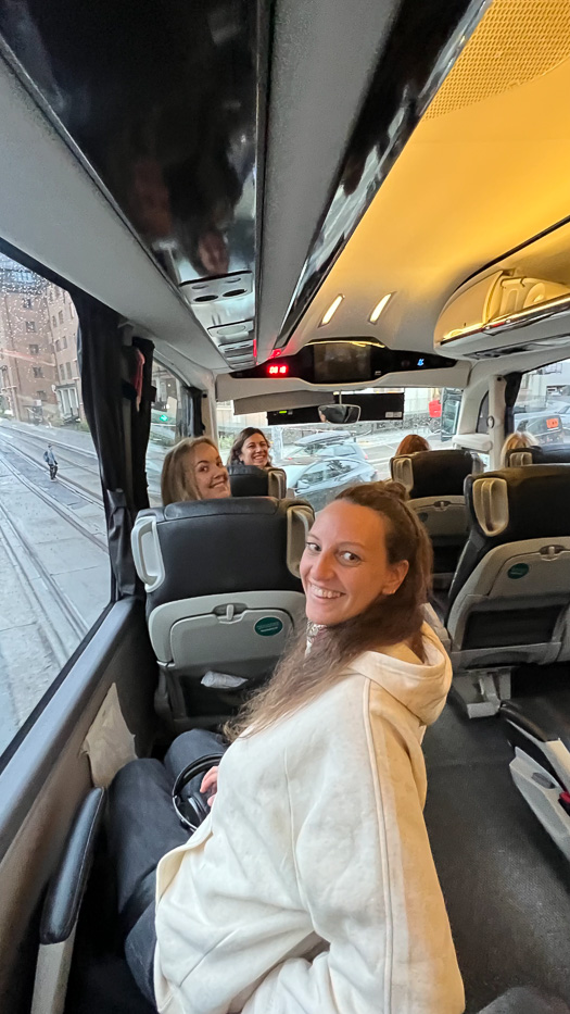 bilde fra innsiden av en buss med tre smilende kvinner