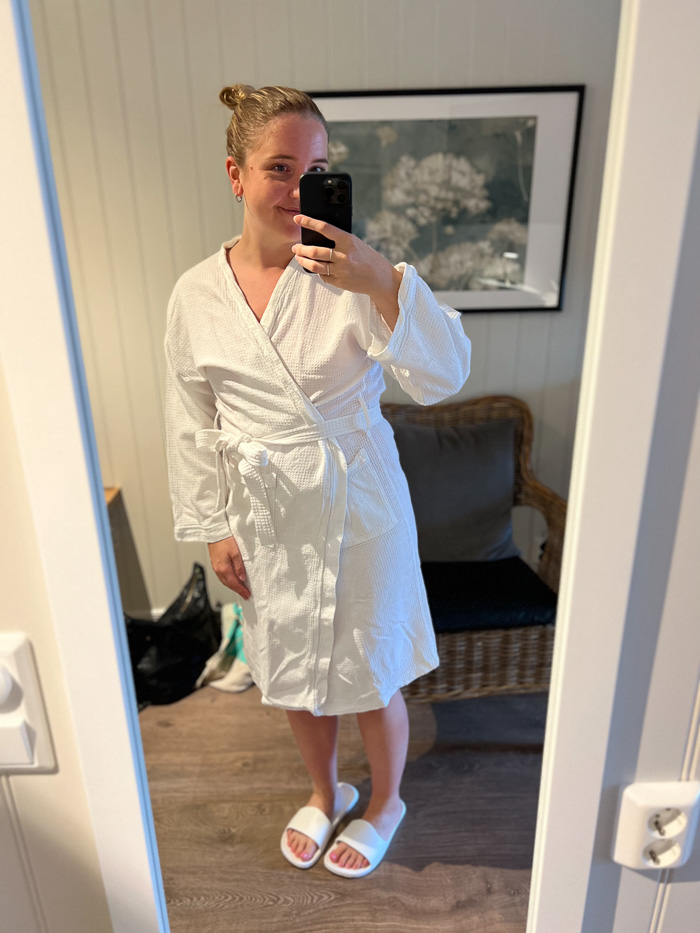 smilende kvinne iført badekåpe og tøfler tar en selfie i speilet på Katrinelund Gästgiveri & Sjökrog