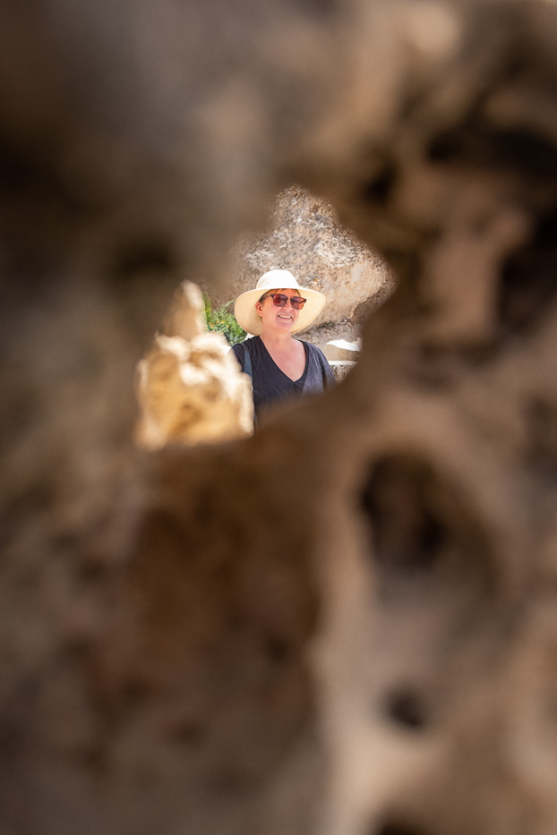 a smiling woman with a hat photographed through a rock