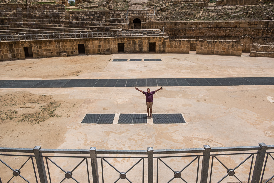 a man standing inside the uthina amphiteatre with his hands stretched out