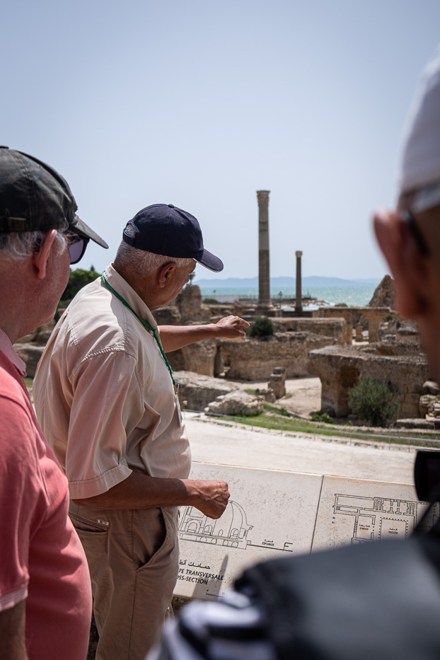 en mann med caps peker mot historiske ruiner i karthago