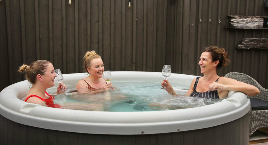 three smiling women in a hot tub