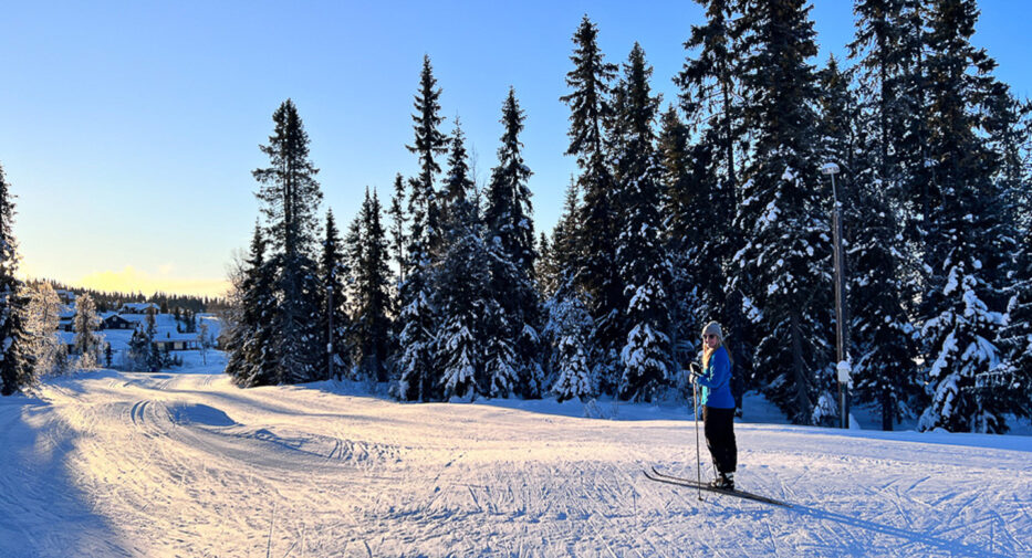 woman smiling while skiing in a snowy forest