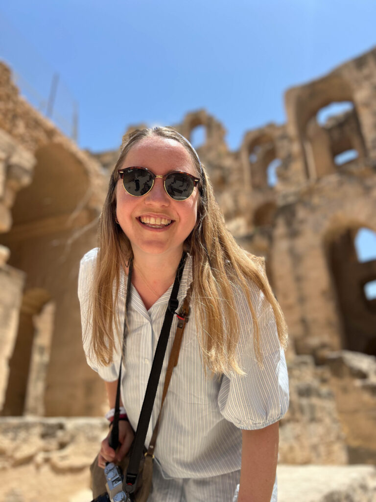 close-up of a smiling lady standing inside the ruins of the amphiteater in el jem