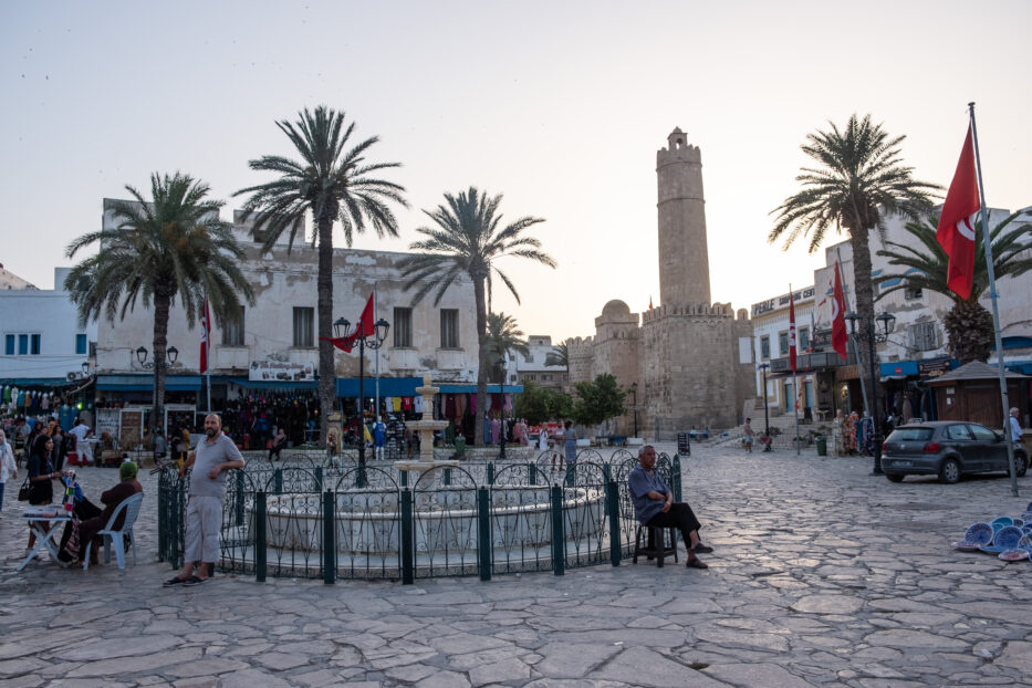 kvinner og menn slapper av foran en fontene på torget i sousse